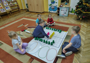 Julek układa kolorowy kubeczke na macie do kodowania.