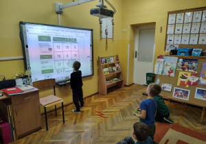 Leoś układa matematyczne puzzle na tablicy matematycznej.