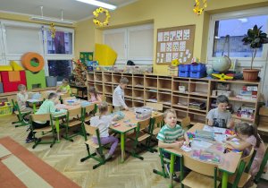 Dzieci rozwiązują karty pracy z klockami.