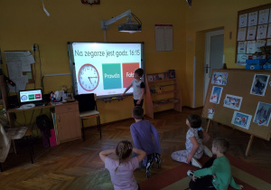 Dzieci rozwiązują zadania zegarowe na tablicy interaktywnej.