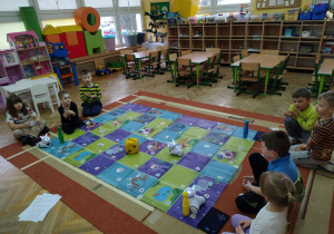 Dzieci grają w grę matematyczną robotami Photon na macie do kodowania.