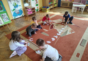 Dzieci rowiazyją matematyczną grę dywanową.