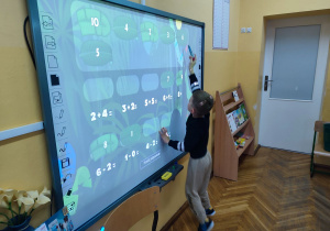 Kacper rozwiązuje zadania matematyczne na tablicy interaktywnej.